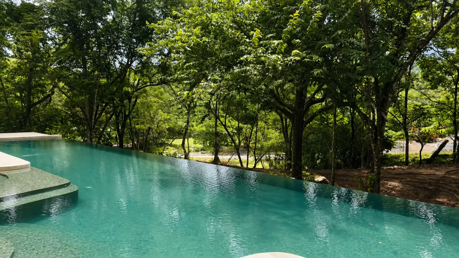 An infinity pool surrounded by tropical trees at Ecovilla San Mateo.
